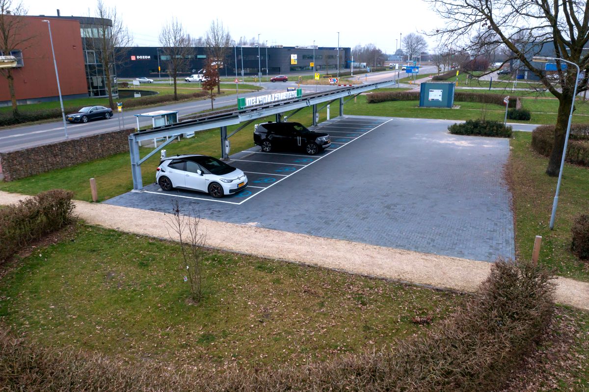 Elektrische auto aan het laden onder de overkapping met zonnepanelen