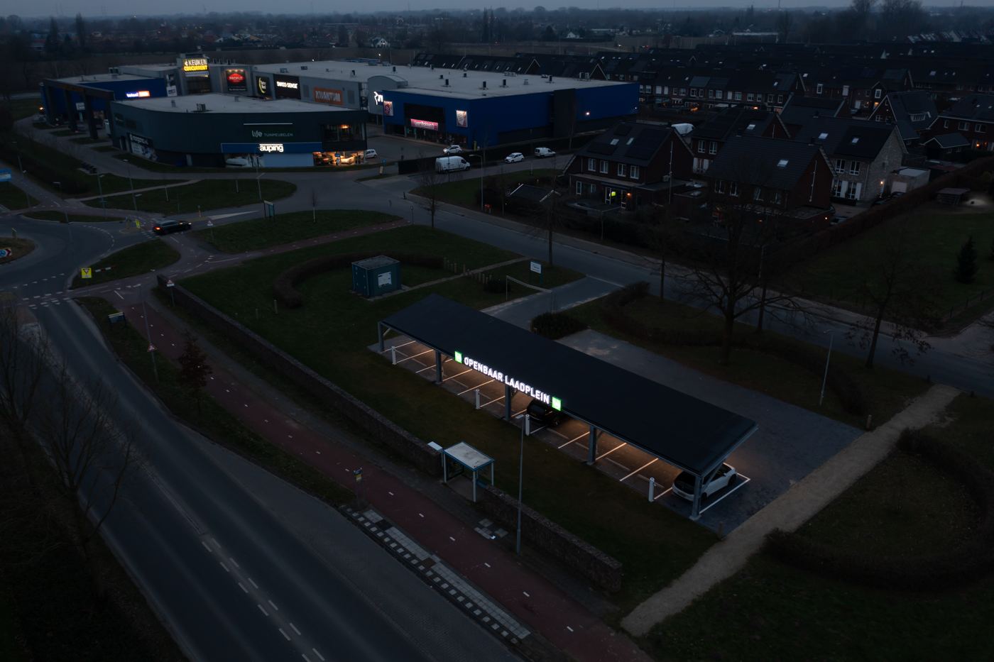 Het laadplein in de avond: verlichte laadplekken en verlichte naam op de overkapping