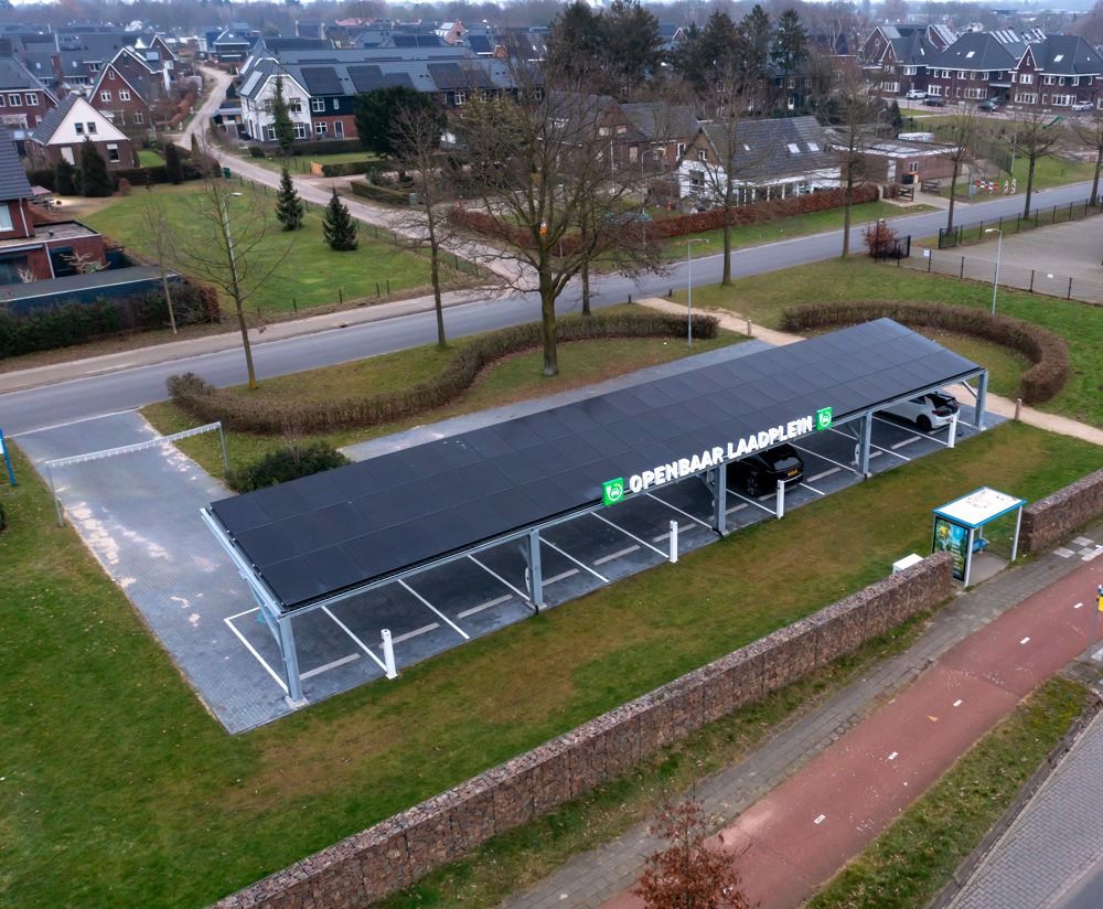 Het laadplein met overkapping en zonnepanelen, met de woonwijk erachter